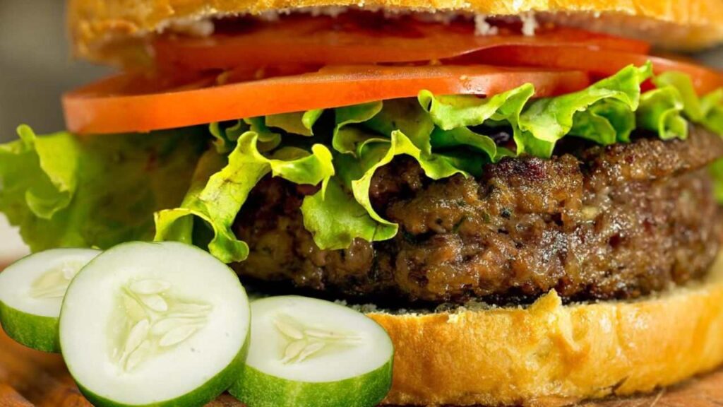Um Delicioso Hambúrguer Fit com carne de frango, folhas de alface, rodelas de tomate e pepino, em pão de batata-doce.